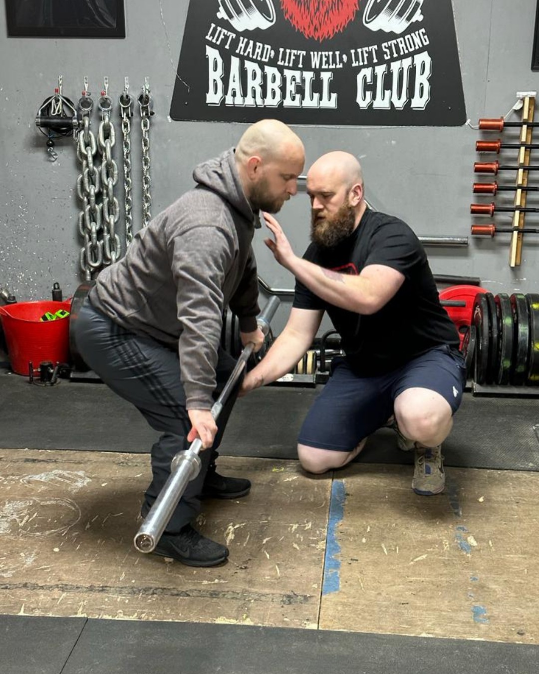A coach at Barbell Club cueing a lifter face to face