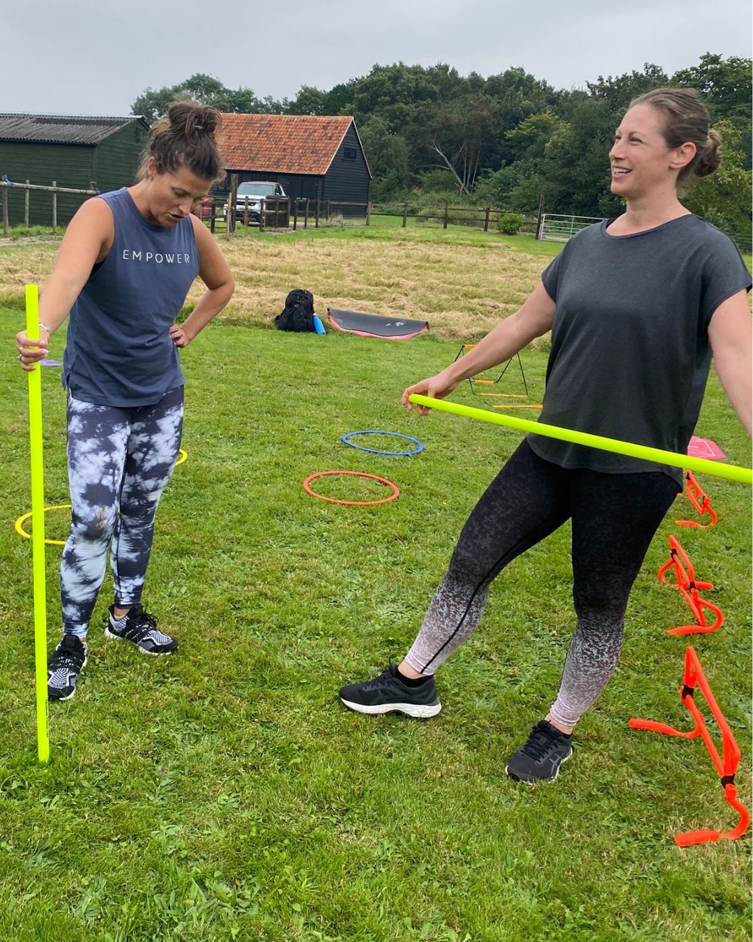 Two women laughing mid-drill with yellow bars